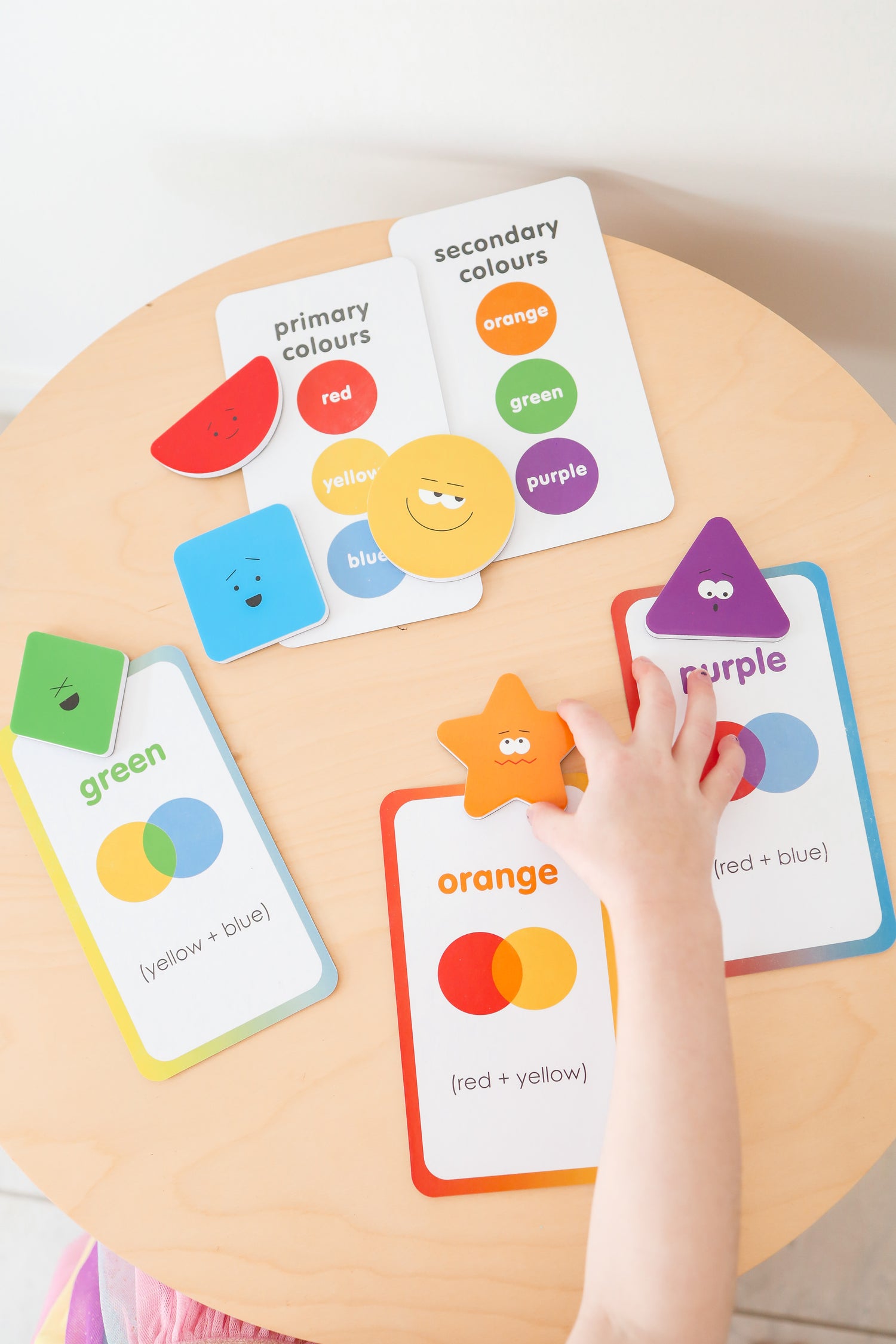 Color learning cards on a wooden table with a child&