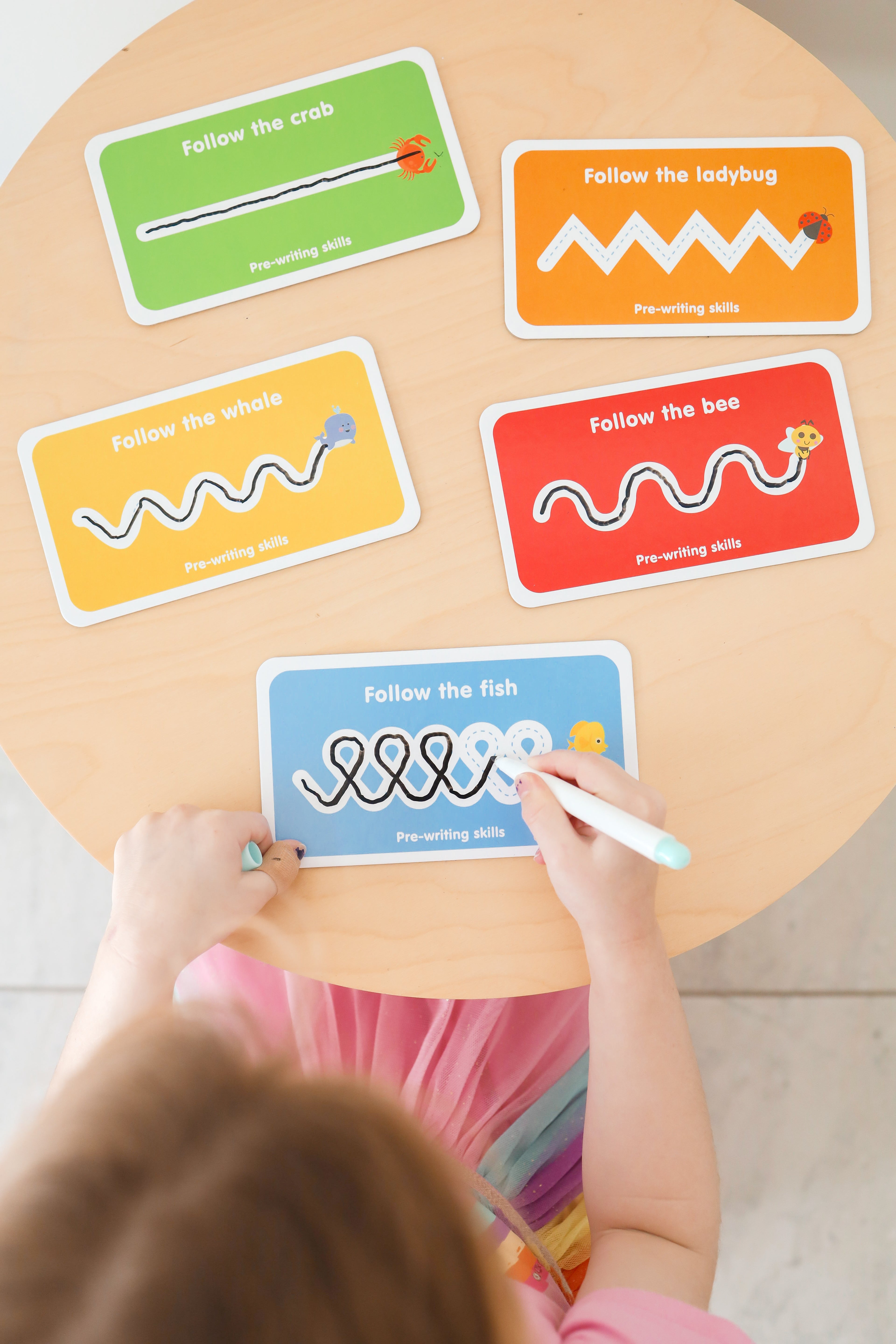 Child playing with educational cards on a wooden table